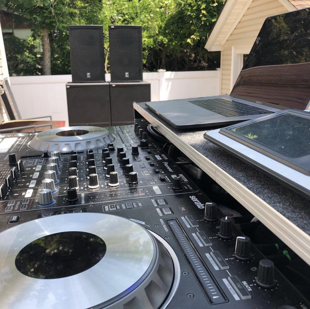 A Pioneer controller in daylight on a patio, with speaker tops stacked on subwoofers behind.
